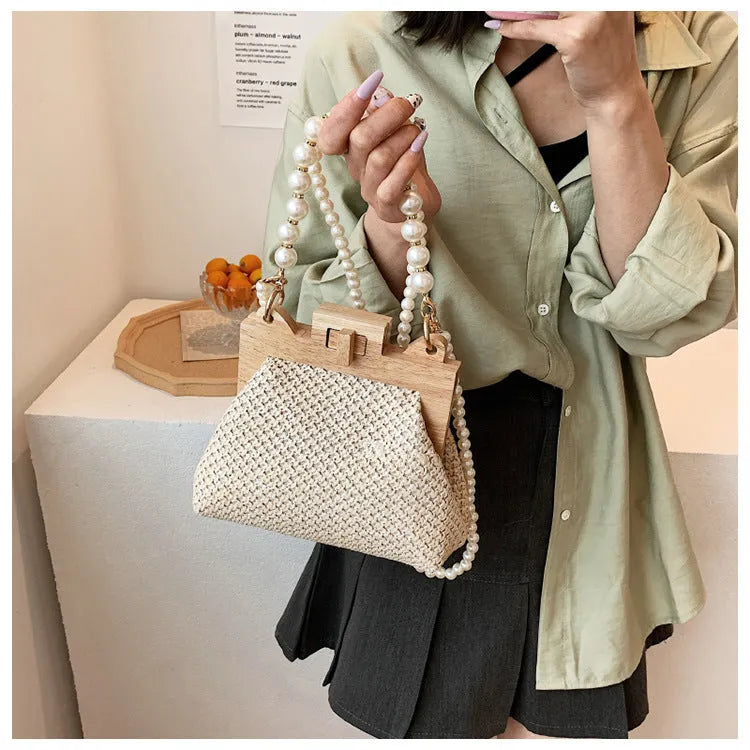 Women's horizontal square straw shoulder bag with pearl chain strap, shown in beige colour with visible sewing line detail.