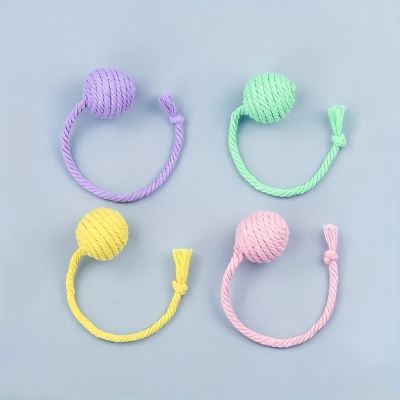 Cat toy ball with rope attached in green, pink, purple, or yellow colours with internal bell
