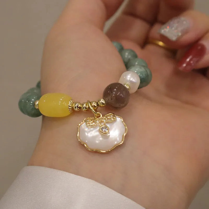 Green jade beaded bracelet with a silver-toned shell charm on an adjustable black cord.