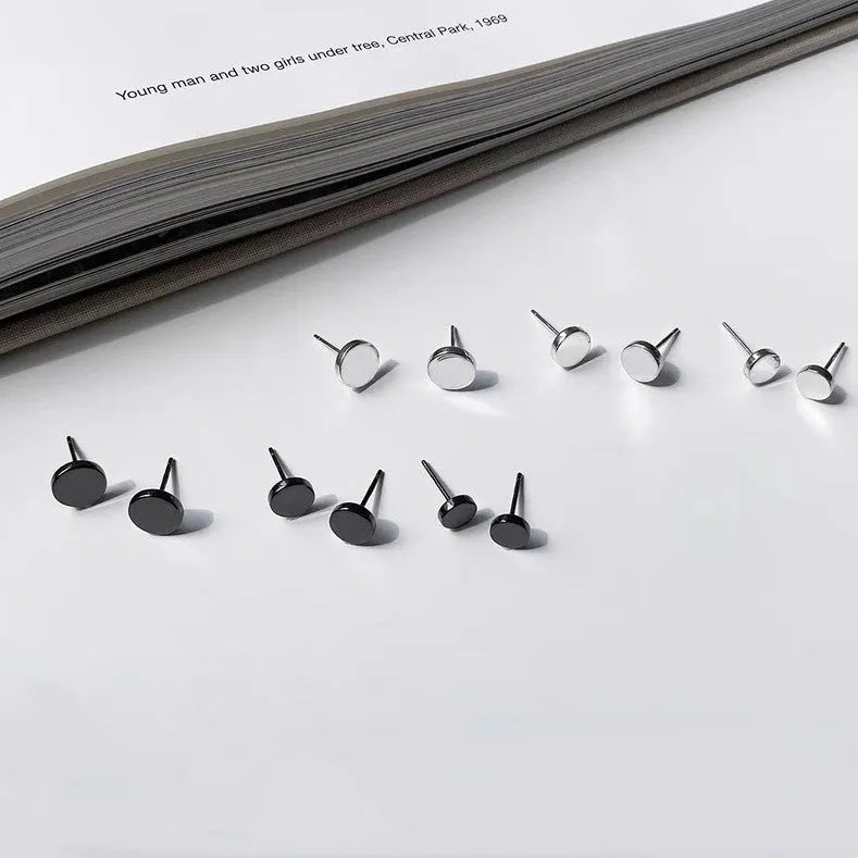 A pair of flat, round S999 sterling silver ear studs on a plain background, shown in silver and black colour options.