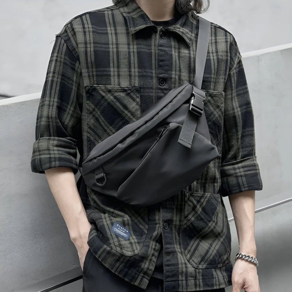 Black slanted chest bag with sewing line details, worn crossbody style