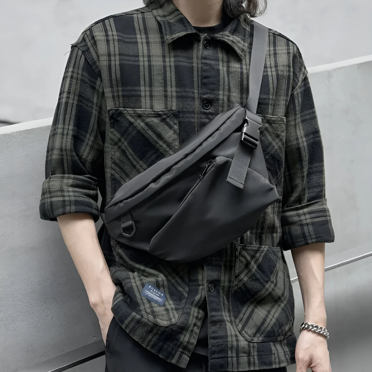 Black slanted chest bag with sewing line details, worn crossbody style