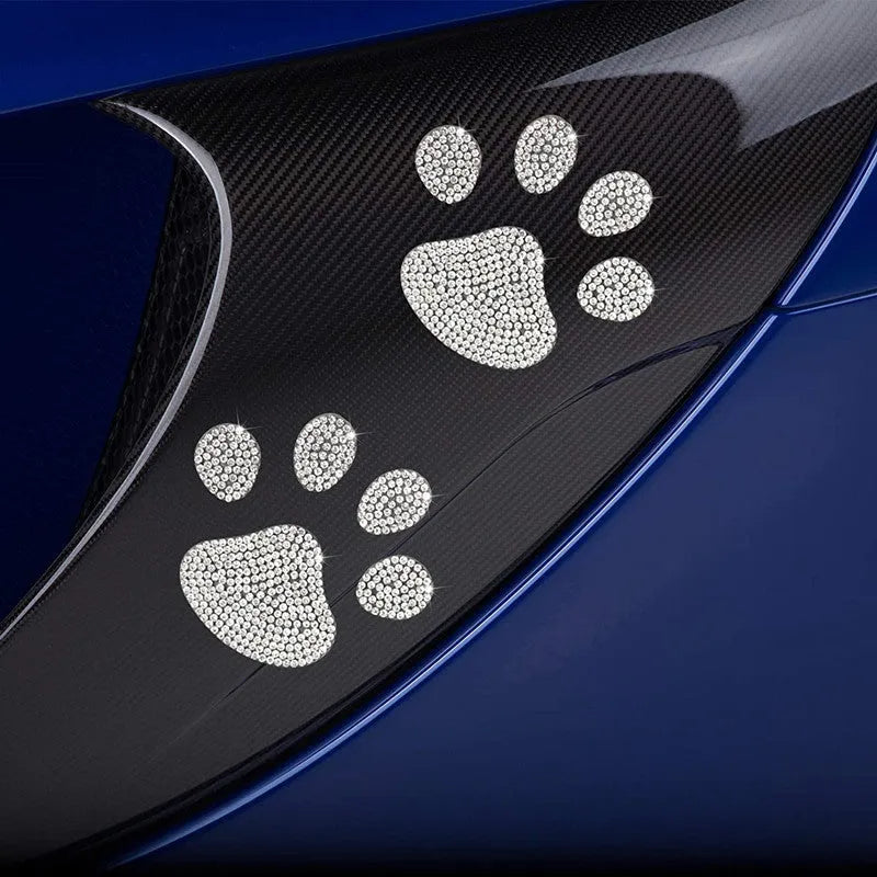 Close-up of a diamond-encrusted glass car sticker in a bear paw or butterfly design on a car surface.