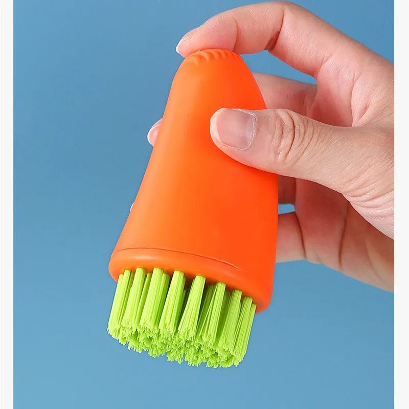 Orange and white carrot-shaped nylon kitchen cleaning brush with radish pattern on a wooden surface.