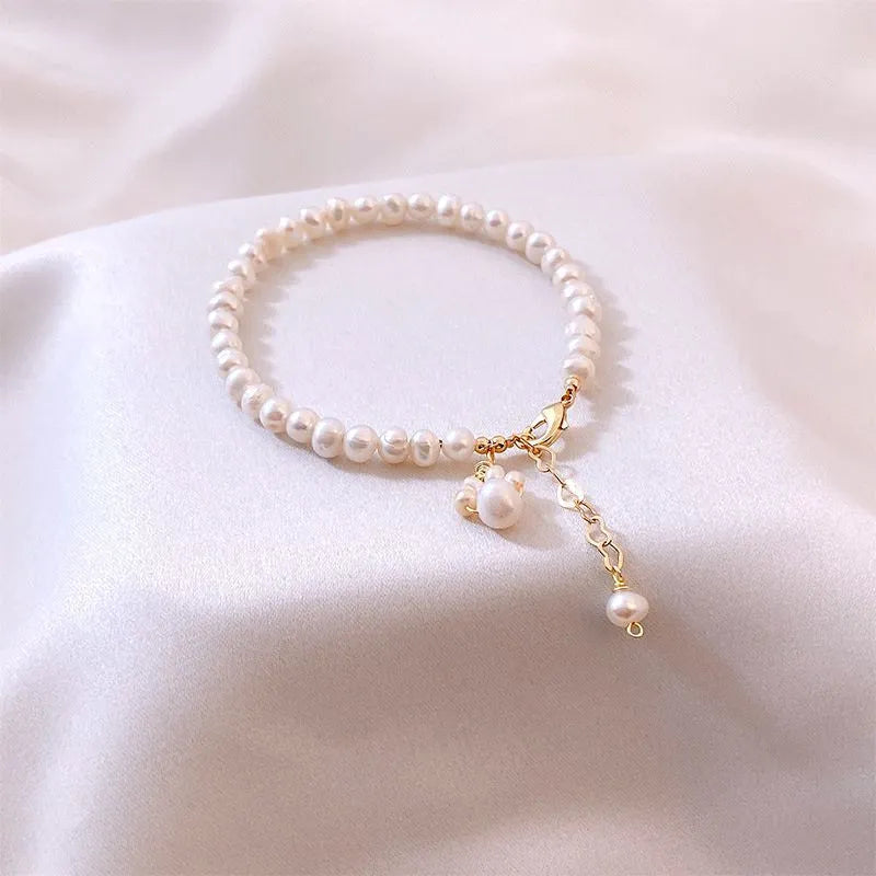 Women's white freshwater pearl cat's paw bracelet with electroplating finish on a neutral background