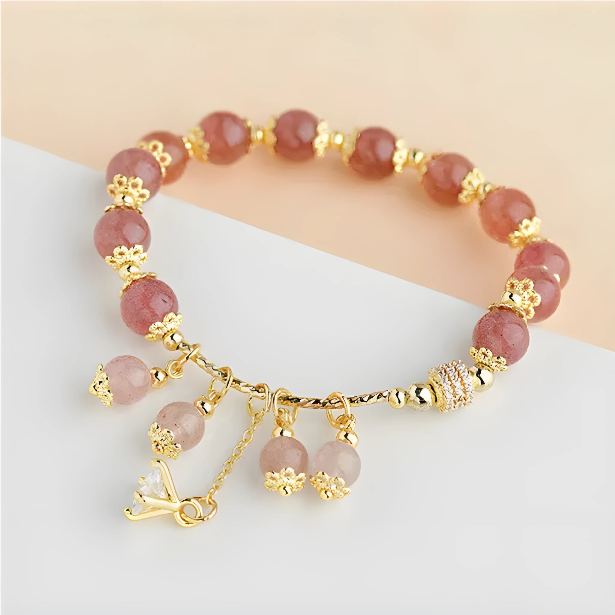 Close-up of a women's pink strawberry quartz heart bracelet with pearl details on a wrist.