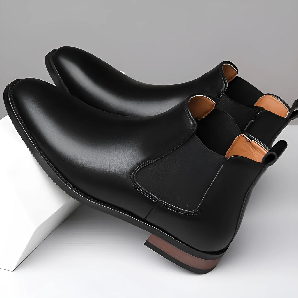 Men's black Chelsea high-top boots with a pointed toe and low rubber sole on a white background.