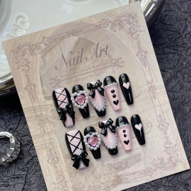 Handmade black and pink heart design artificial nails with bow, Xingx pattern, and cat's eye finish.