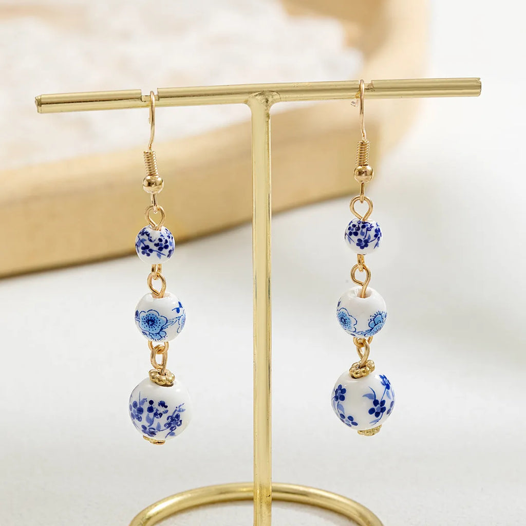 Long retro earrings with blue and white porcelain-coloured ceramic beads and geometric alloy details.