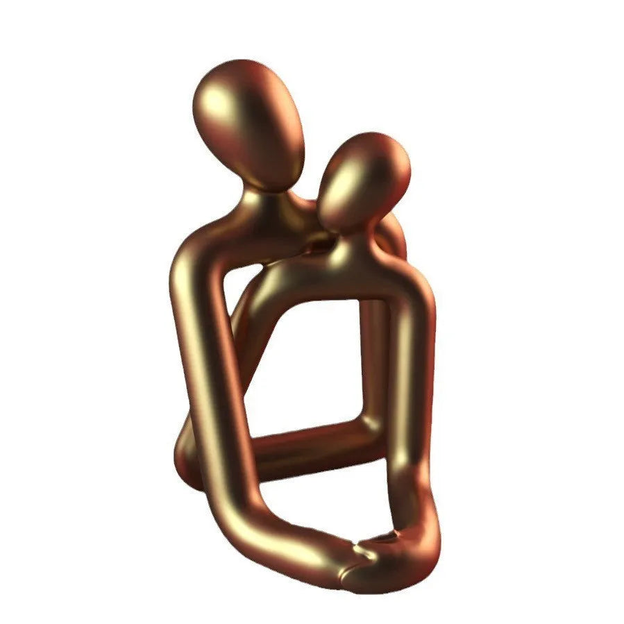 Modern minimalist resin statue of a couple in milky white or gold colour on a wooden surface.