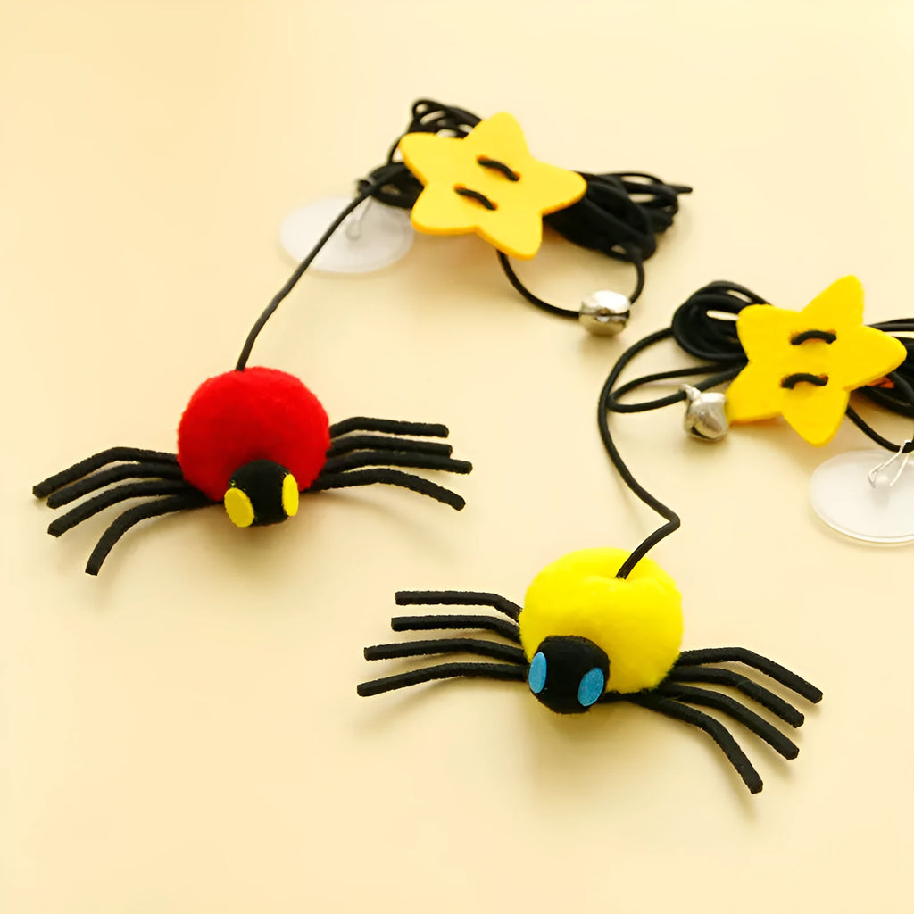 Red and yellow cat toy with feather and bell spider hanging from a door on an elastic rope.