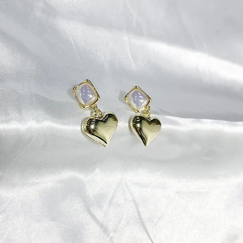 Small gold heart earrings with metal construction and post backing